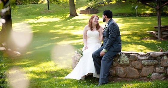 Bride and groom on stone wall.